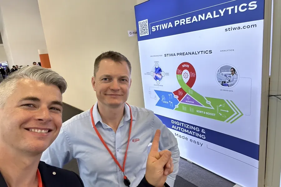 Zwei Personen vor der Präsentationswand des STIWA Preanalytic Loop auf einer Messe